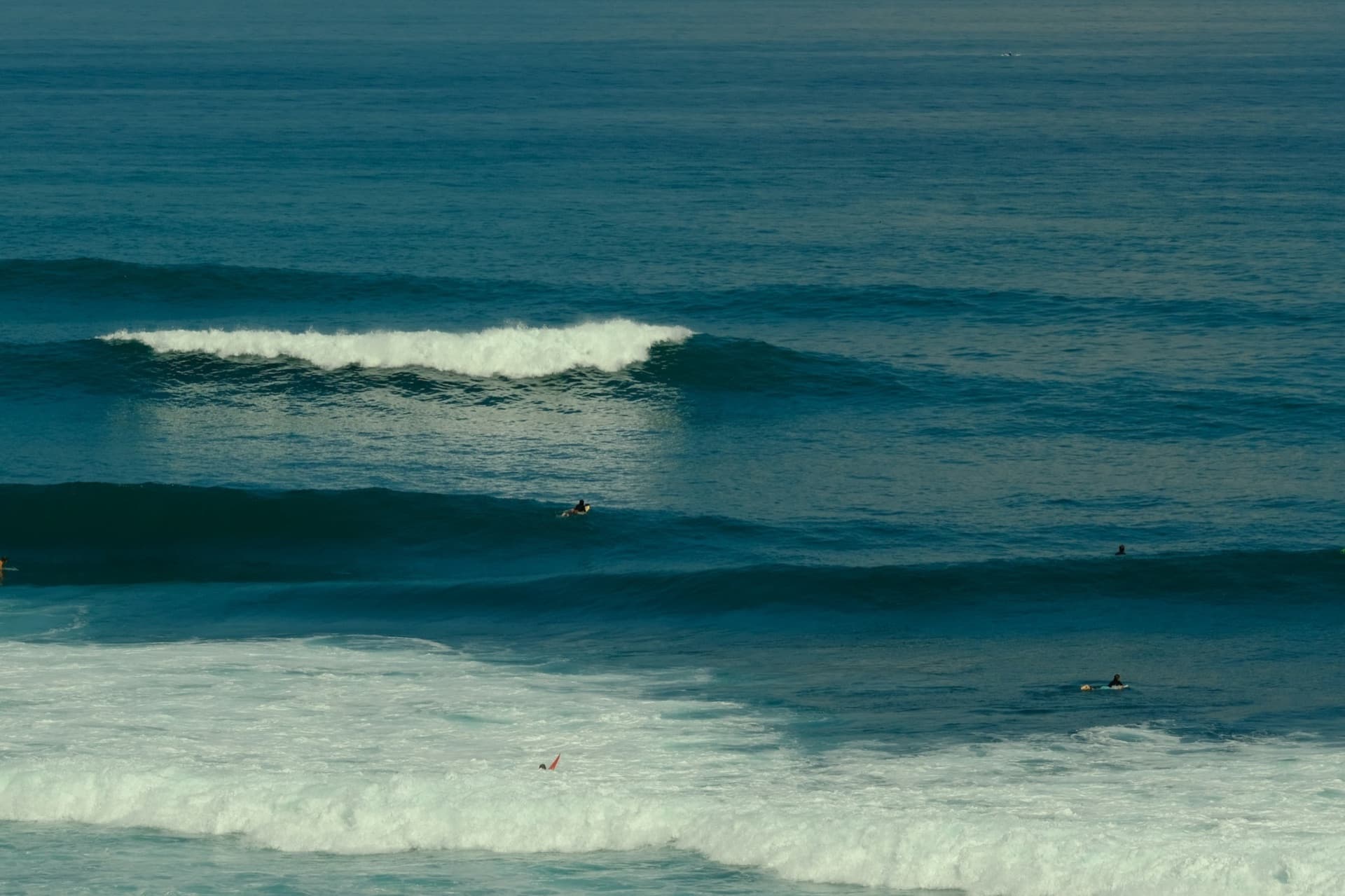 A long left-hand wave peeling along the reef at Uluwatu, Bali, with the clifftop temple behind