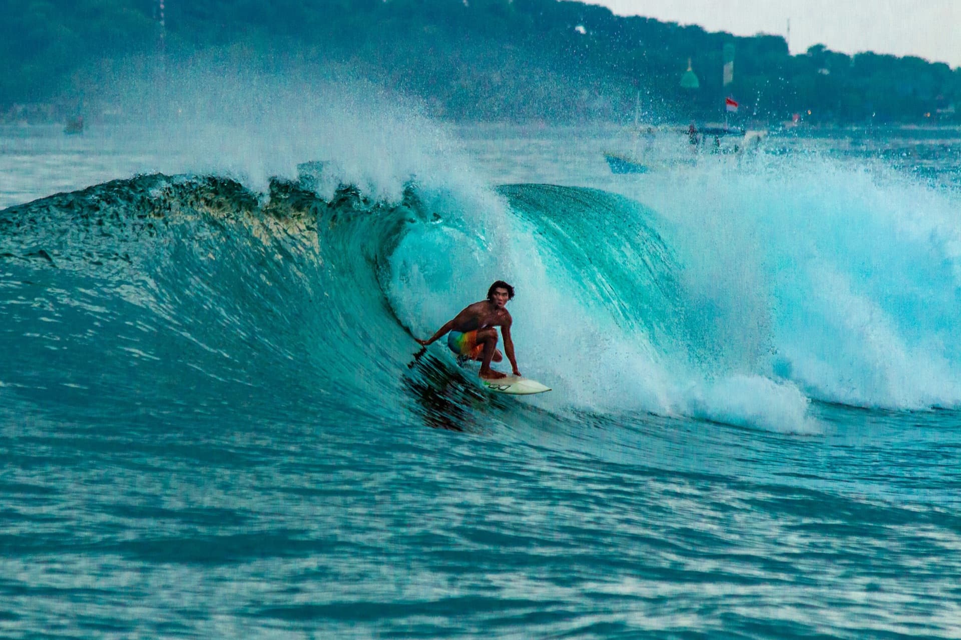A long left-hand wave peeling along the reef at Uluwatu, Bali, with the clifftop temple behind