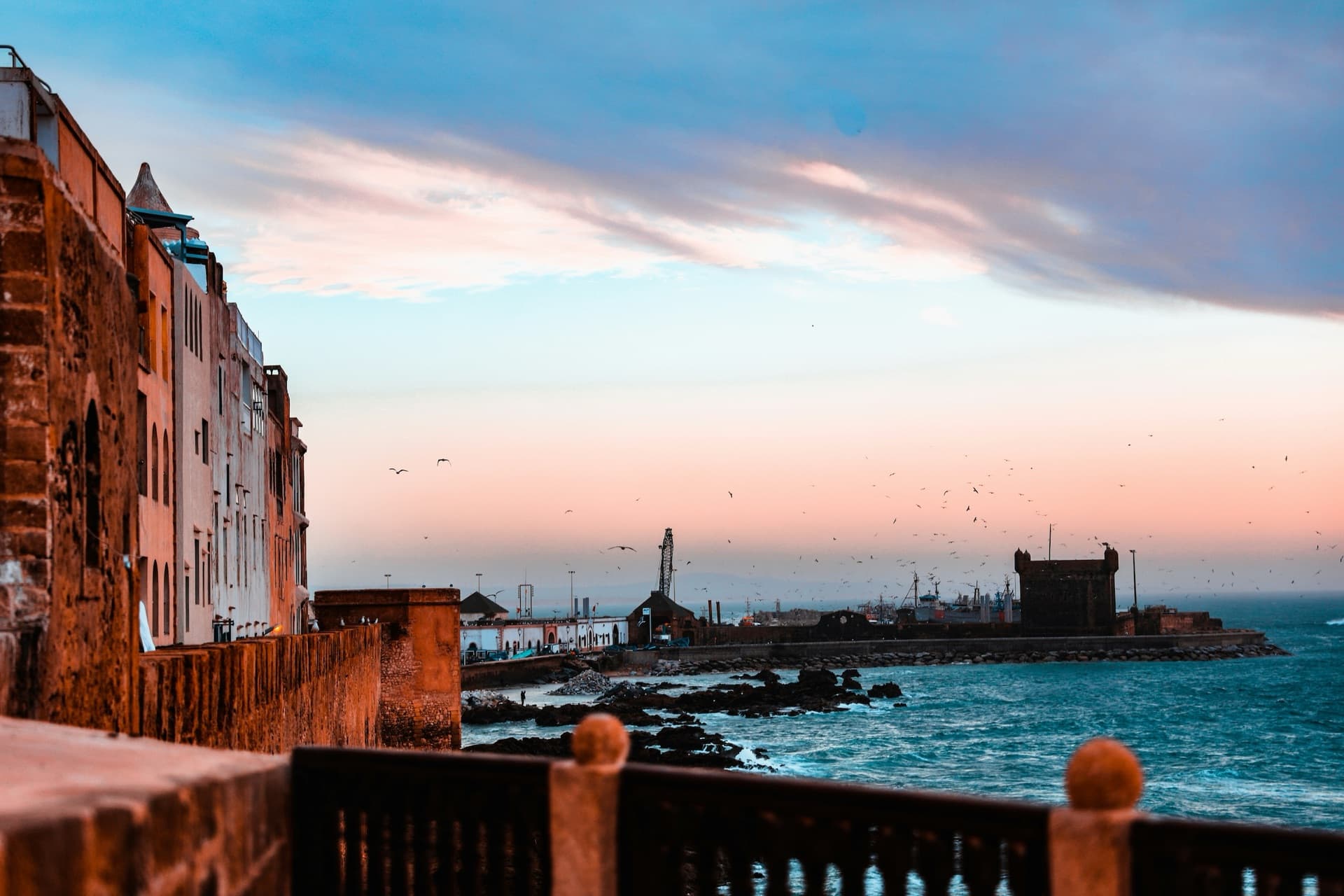 The medina ramparts and fortified harbour of Essaouira at sunset, the Atlantic beyond