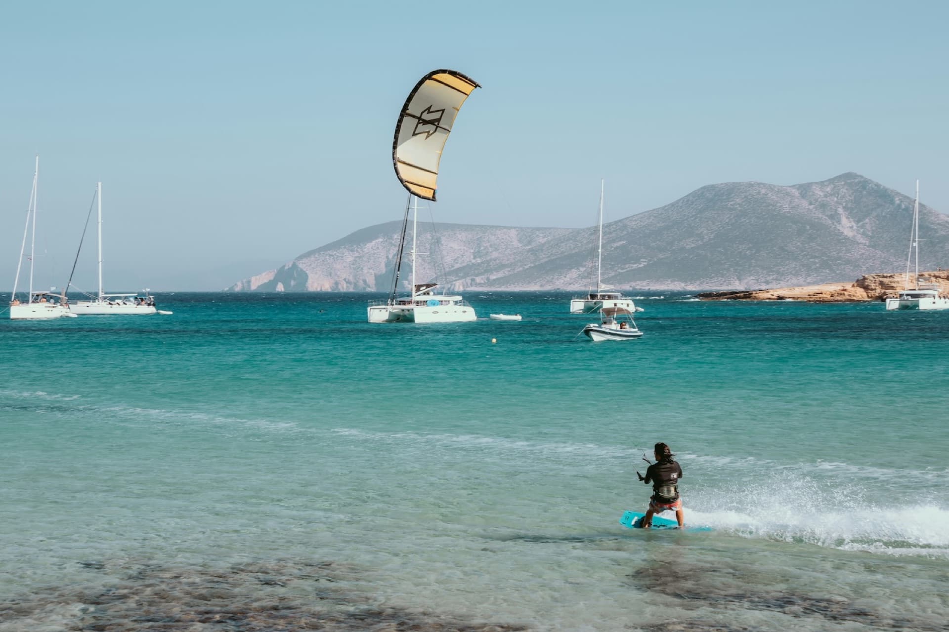 Kitesurfers on turquoise water off a Greek island beach in summer