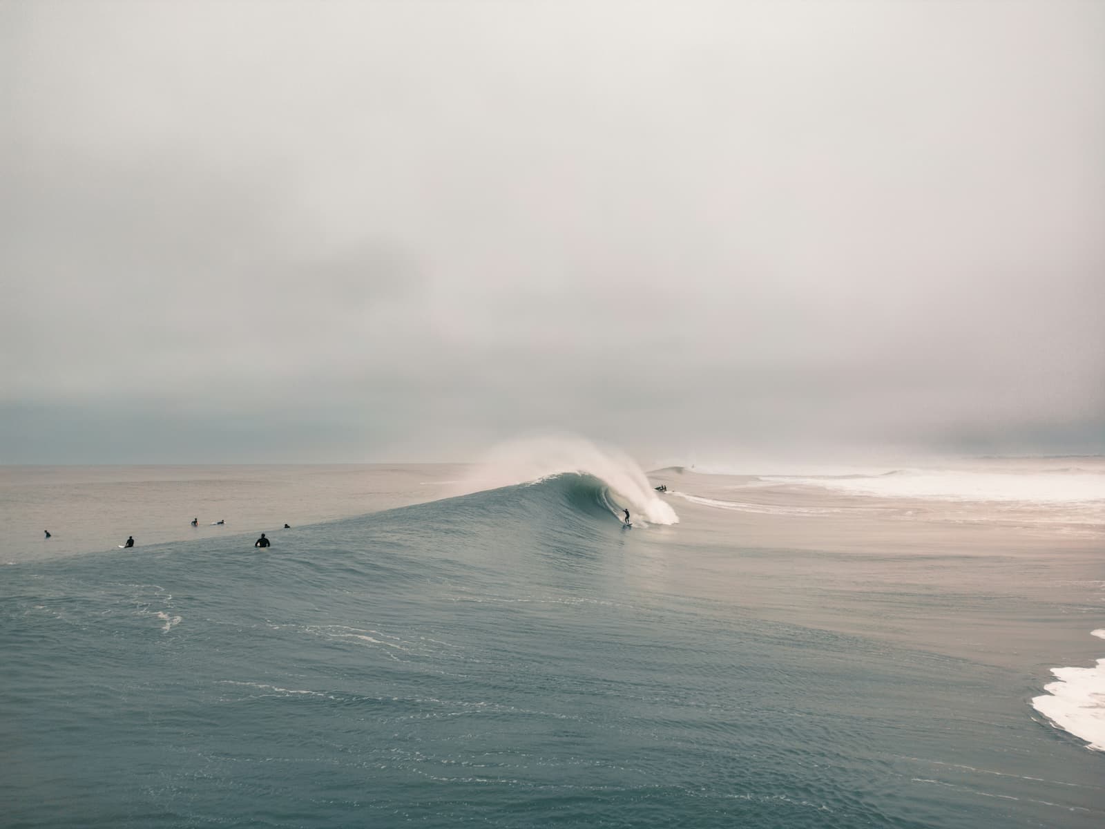 A surfer dropping into a hollow beach-break wave at Hossegor on a clean autumn morning