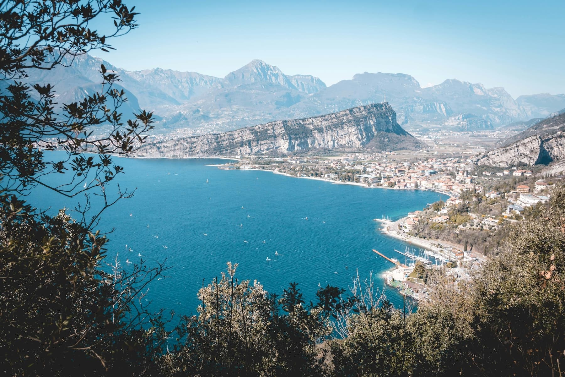 Windsurfers planing on Lake Garda below steep cliffs near Torbole on the afternoon Ora