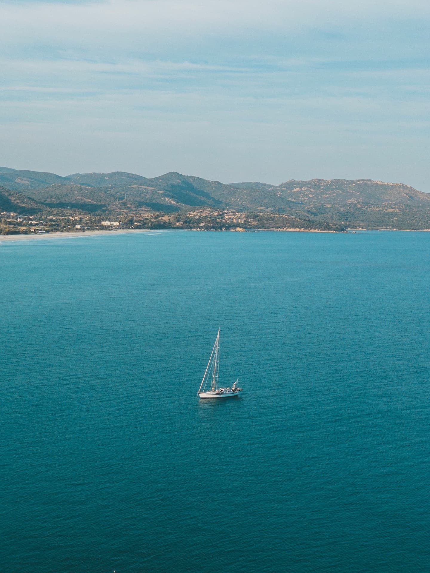 A sailboat anchored on deep blue water off the Sardinian coast