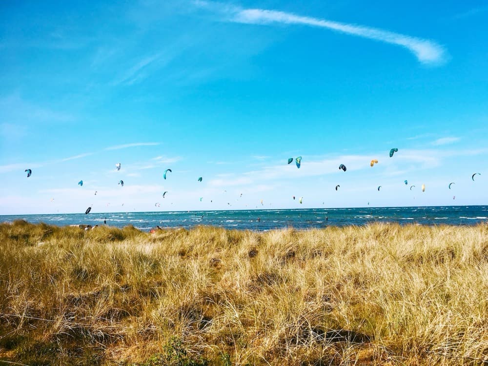 A wide shallow bay on Fehmarn with kitesurfers and flat water