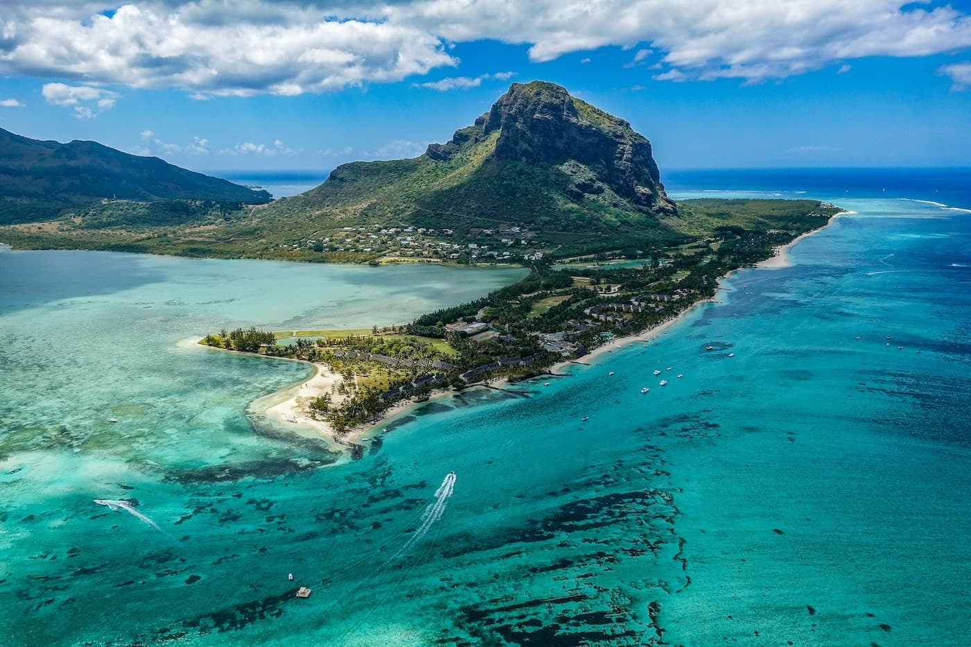 A kitesurfer on the turquoise lagoon at Le Morne beneath the Le Morne Brabant cliff in Mauritius